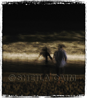 Night shot of two young people running on beach towards ocean 