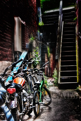 A pack of bikes and motorcycles in an alley